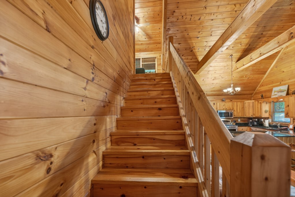 Warm wooden staircase leading to a cozy loft area in a rustic cabin.
