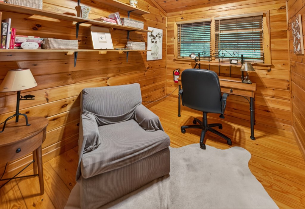 Cozy study nook with wooden walls, comfy chair, and desk for a peaceful work environment.
