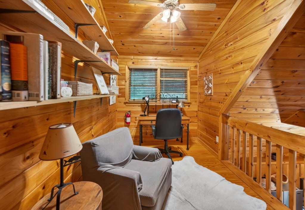 Cozy reading nook with rustic wood paneling and a desk for quiet study or work.