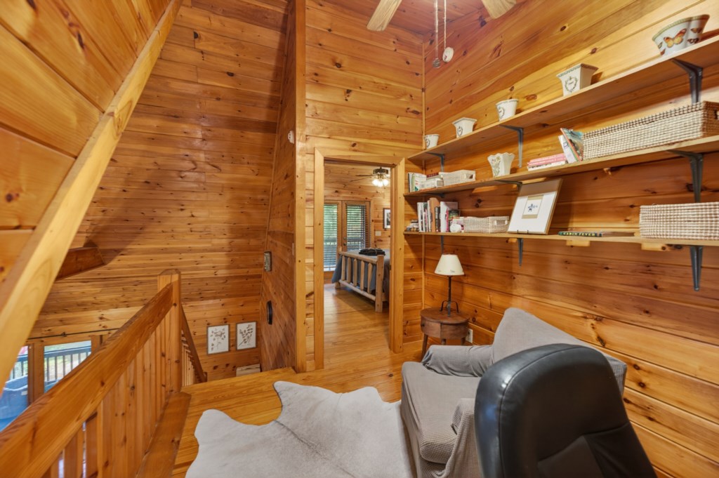 Cozy reading nook with rustic wood walls and ample shelving for a relaxing retreat.