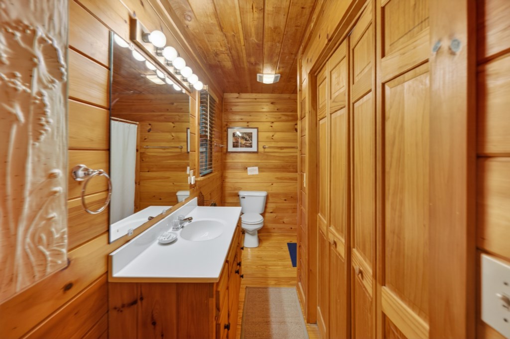 Cozy wooden bathroom with ample storage and bright vanity lighting.