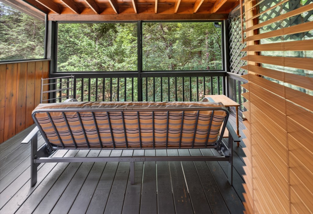 Relax on the screened porch with serene forest views and cozy seating.