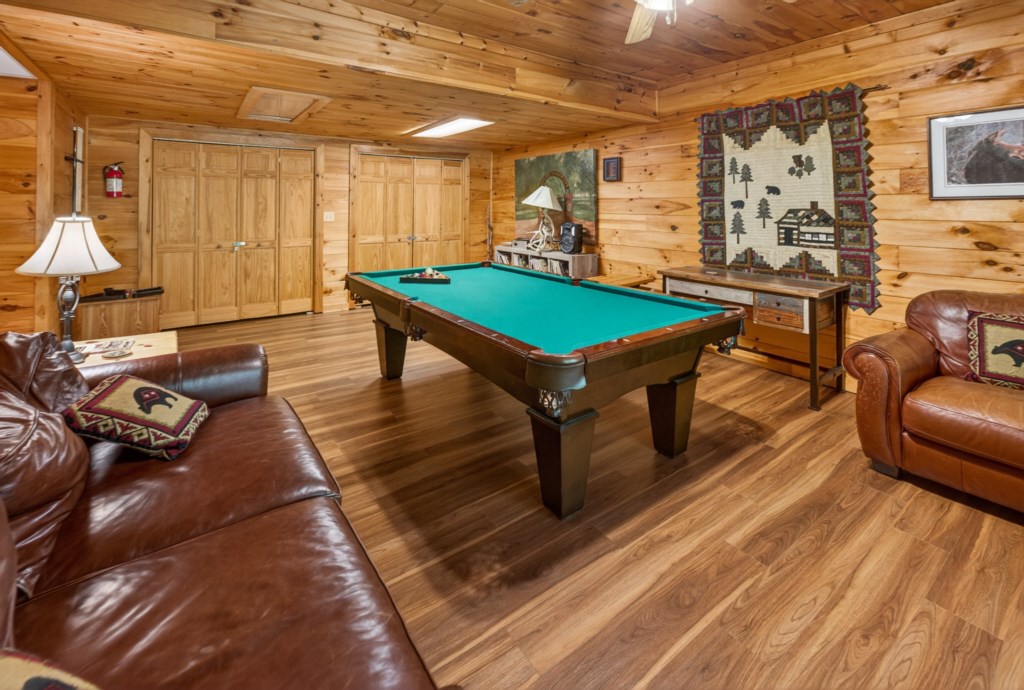 Rustic game room with a pool table and comfy leather seating for relaxation.