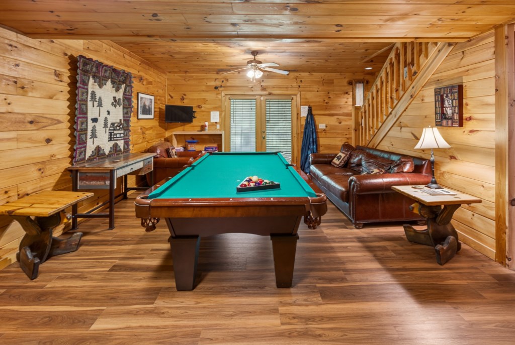 Rustic game room with a pool table and cozy leather seating.