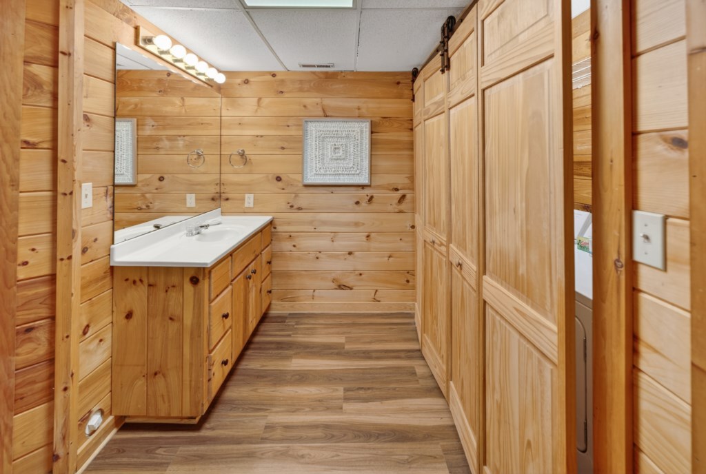 Rustic bathroom with wood paneling and a spacious vanity for your convenience.