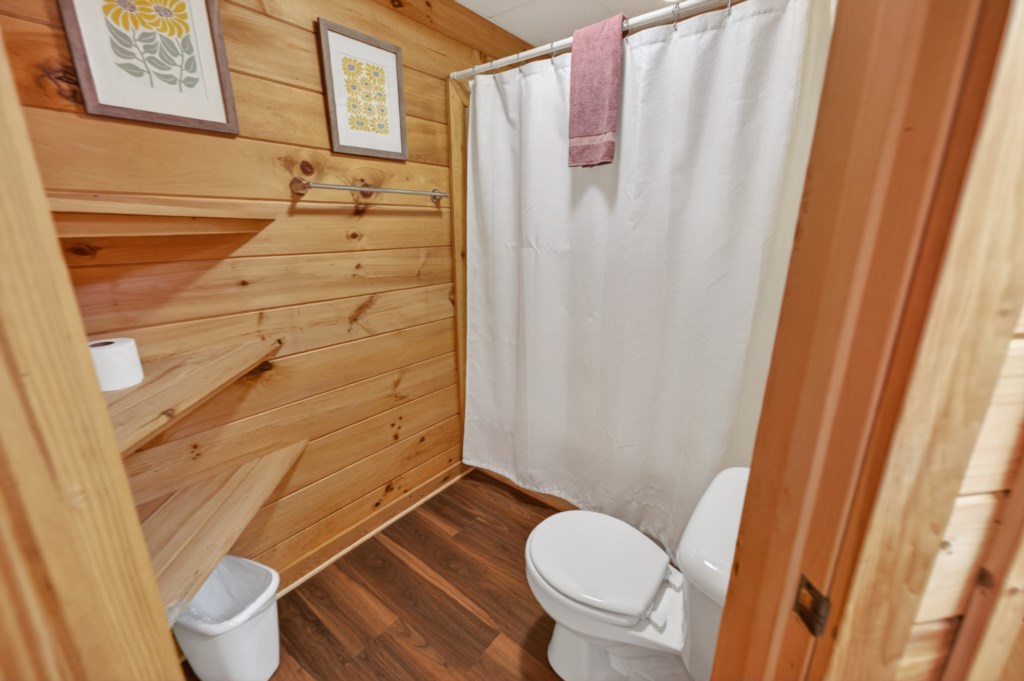 Cozy bathroom with rustic wood paneling and convenient shelving.
