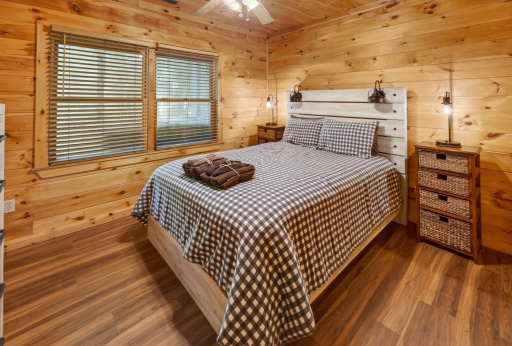 Cozy cabin bedroom with rustic wood paneling and warm lighting for a restful stay.