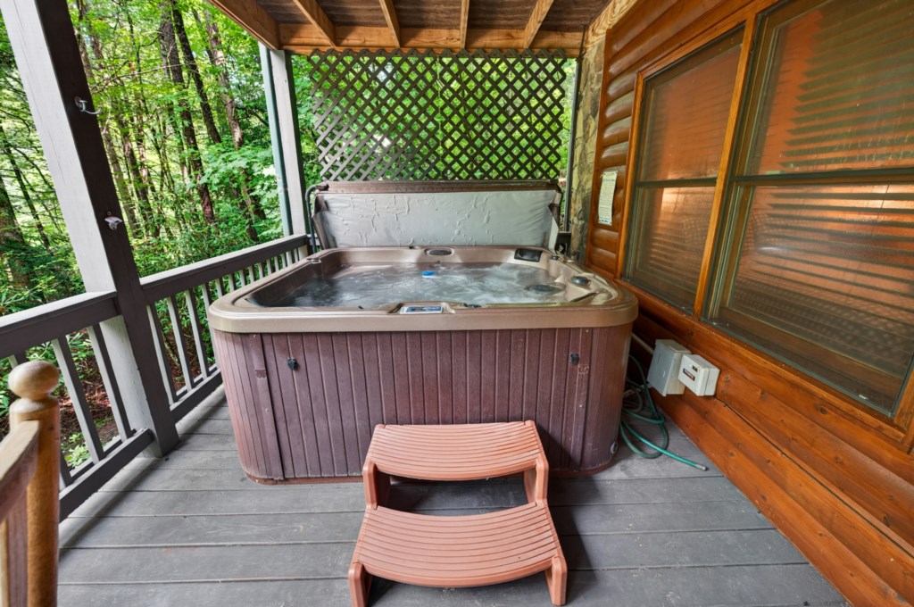 Secluded hot tub on a private deck surrounded by lush forest views.