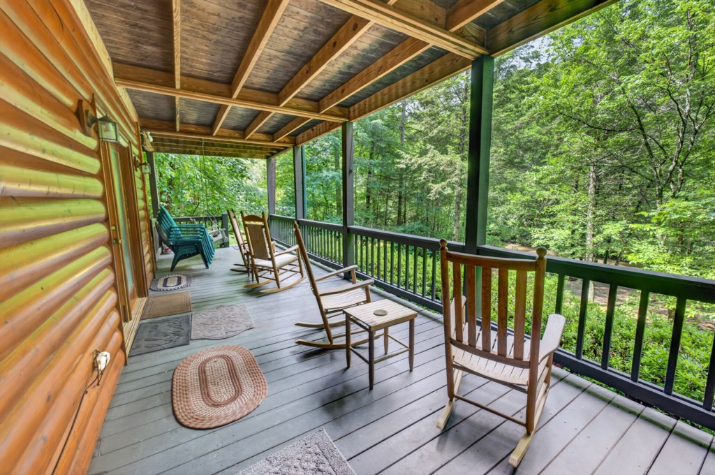 Relax on the covered porch with serene forest views and cozy rocking chairs.