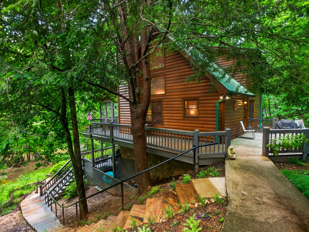 Charming log cabin nestled in lush forest with spacious deck for outdoor relaxation.