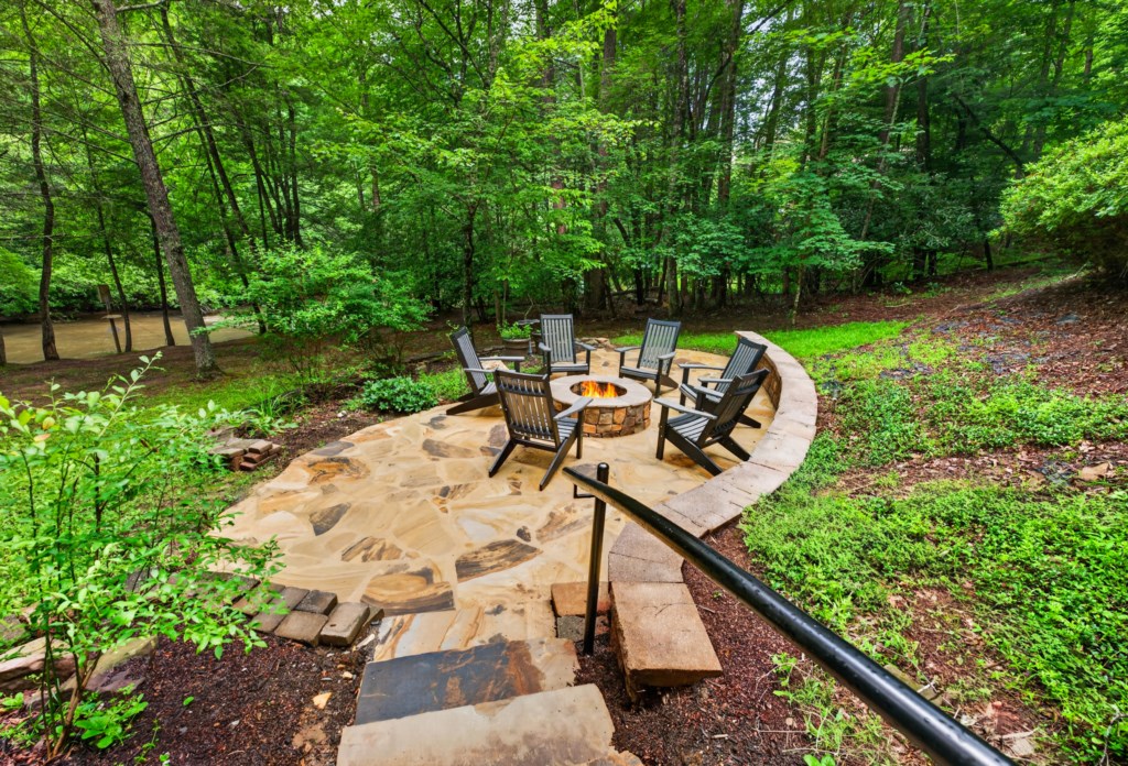 Tranquil outdoor firepit area surrounded by lush forest, perfect for evening gatherings.