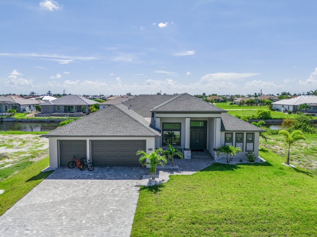 Modern home with a large driveway and beautifully landscaped entrance.