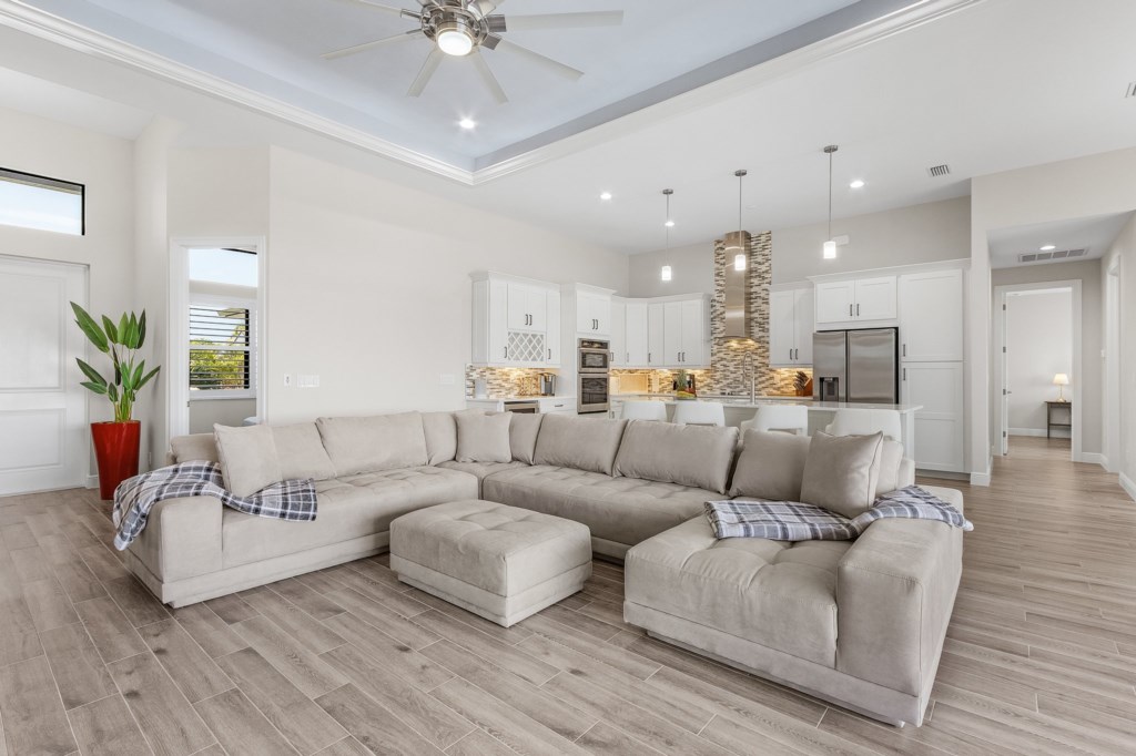 Spacious open-plan living room with a large sectional and easy access to the modern kitchen.