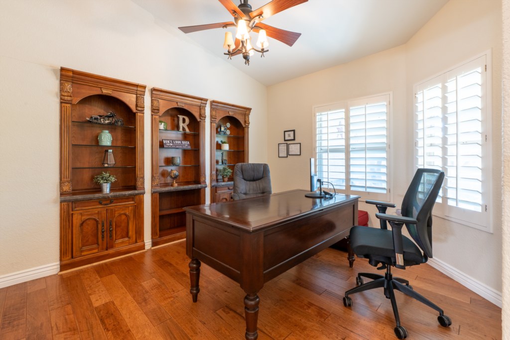 Elegant home office with wooden shelves and natural light, ideal for remote work.
