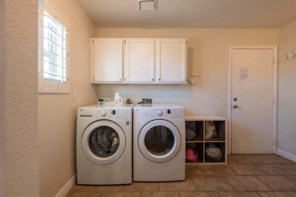 Convenient laundry room with modern washer and dryer, plus storage space.