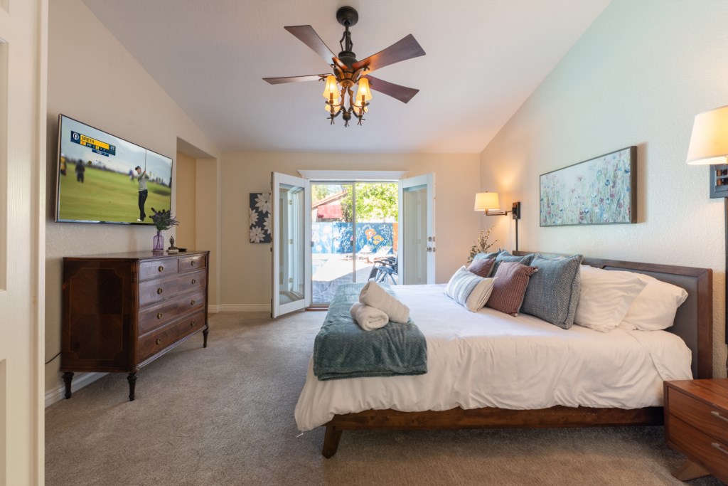 Spacious bedroom with patio access, TV, and elegant decor for a relaxing retreat.