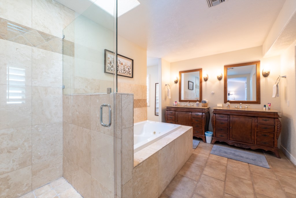 Elegant bathroom with dual vanities, soaking tub, and glass-enclosed shower.
