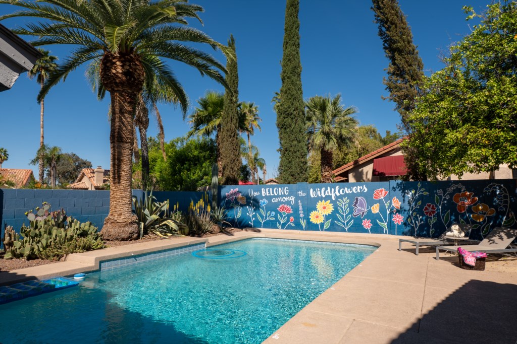 Relax by the vibrant pool with a colorful mural and lush palm trees.