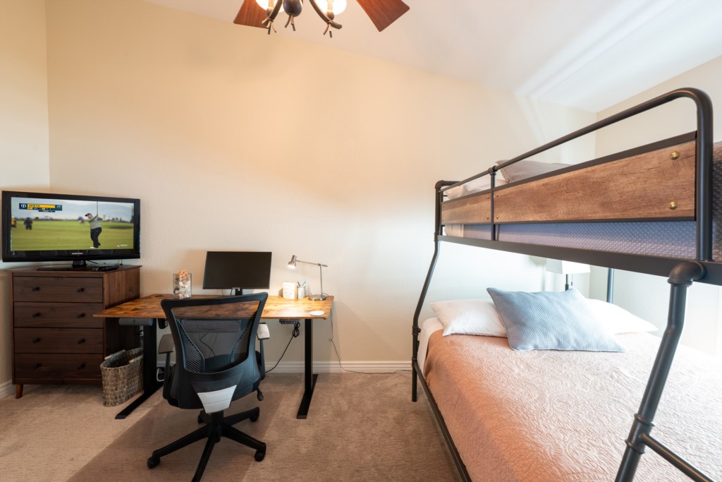 Cozy bedroom with bunk bed, desk, and TV—ideal for work and relaxation.