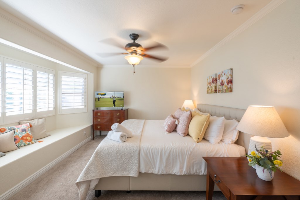 Cozy bedroom with plush pillows, a TV, and a charming window seat for relaxation.