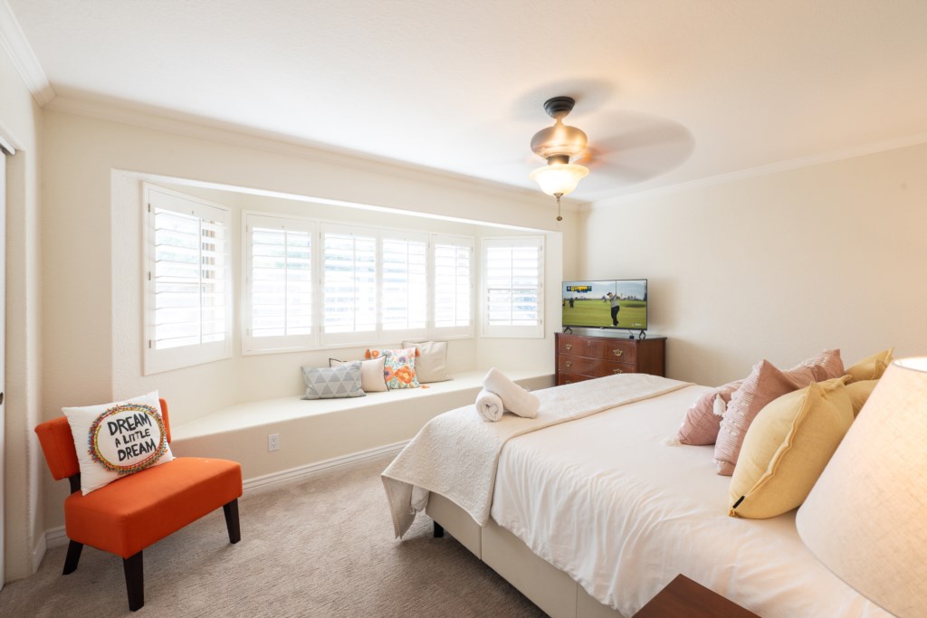 Cozy bedroom with a window seat and TV, perfect for relaxing evenings.