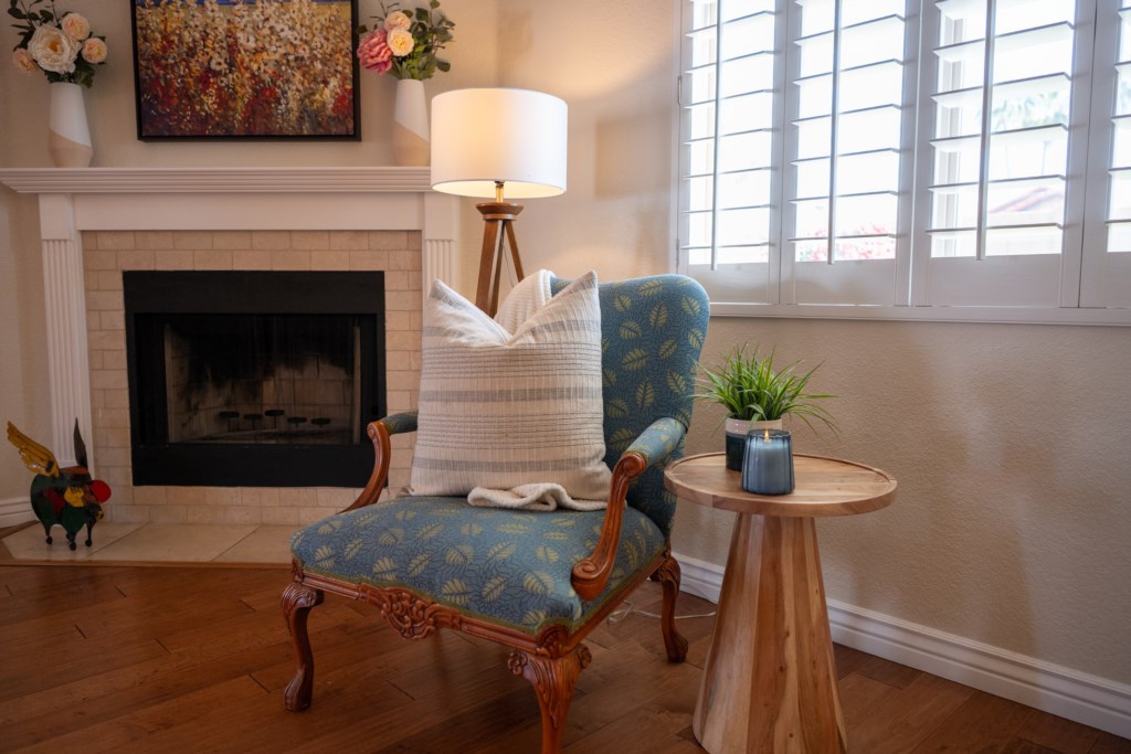 Cozy reading nook by the fireplace with plush armchair and natural light.
