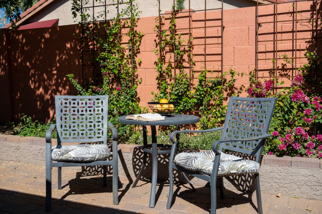 Charming patio area with seating, perfect for enjoying a sunny morning with a book and fresh fruit.