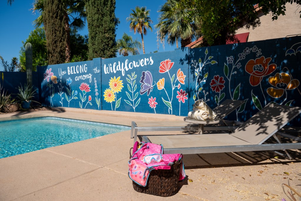 Charming pool area with colorful mural and comfy loungers for a relaxing retreat.