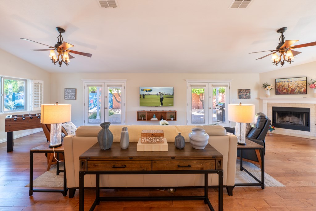 Spacious living room with cozy fireplace, foosball table, and garden views through glass doors.