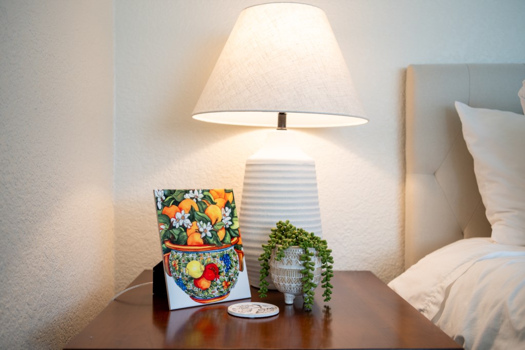 Cozy bedside setup with a decorative lamp and colorful art piece for a relaxing ambiance.