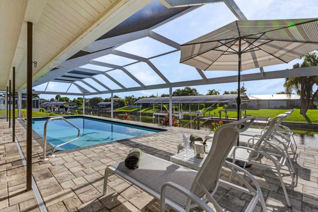 Enjoy sunny days by the pool in the shaded seating area, perfect for relaxation.