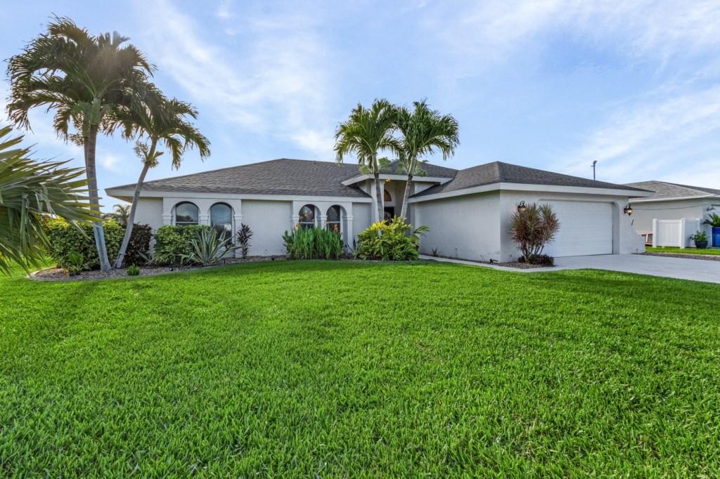 Beautiful front yard with lush green lawn and palm trees, welcoming you to this serene getaway.