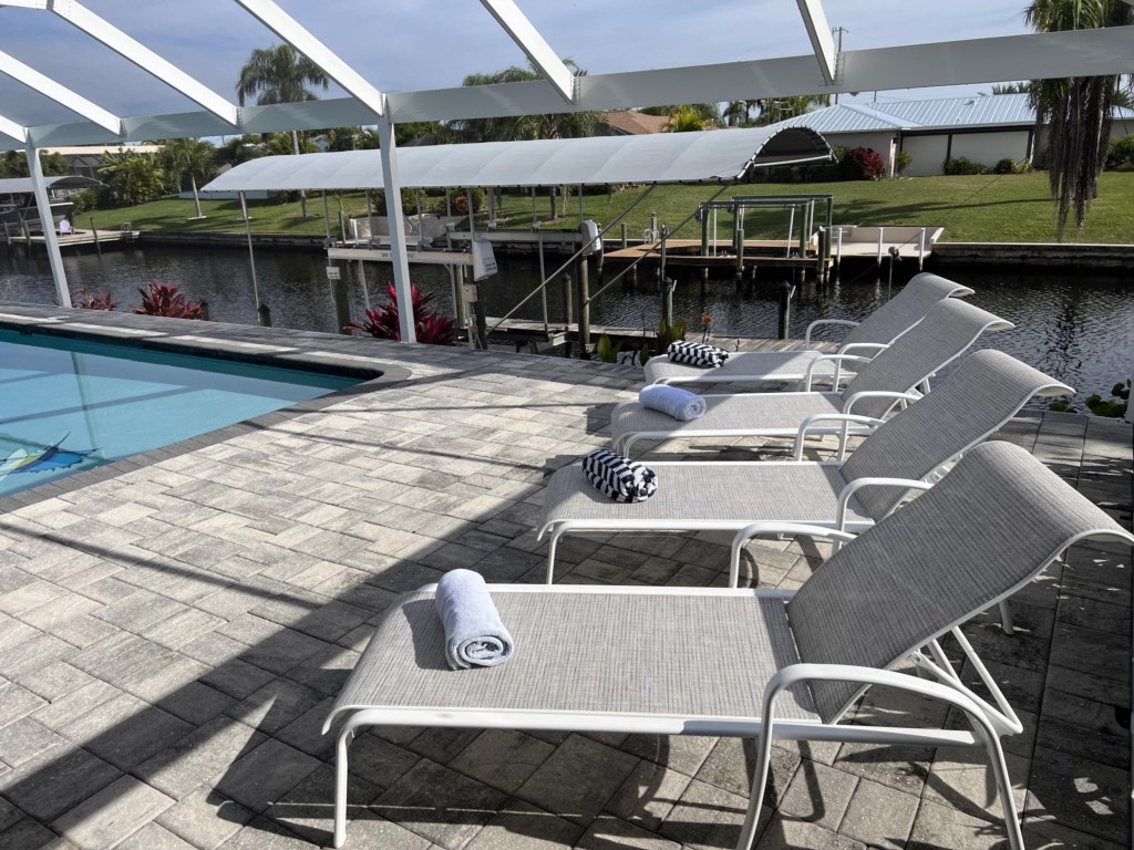 Relax in style on comfortable loungers by the pool with beautiful canal views.