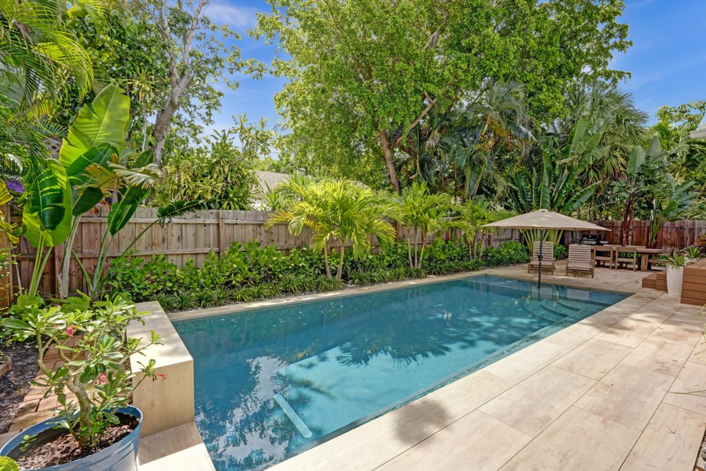 Beautifully landscaped backyard features waterwall pool with in-pool umbrella