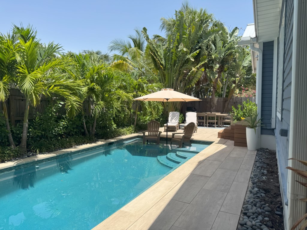 Beautifully landscaped backyard features waterwall pool with in-pool umbrella