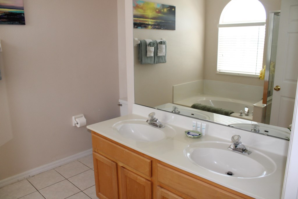 This master bathroom features a dual vanity unit with elegant lighting, providing plenty of counter space 