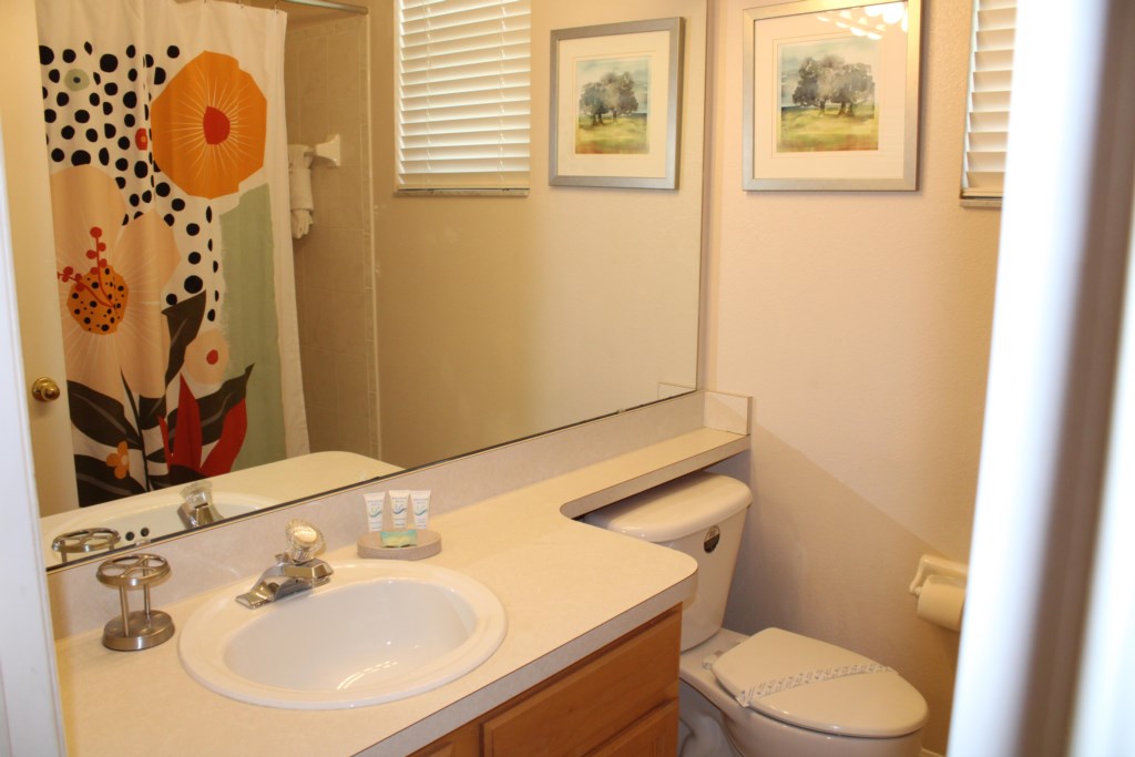 This spacious guest bathroom features a garden tub with an overhead shower, providing convenience for all guests