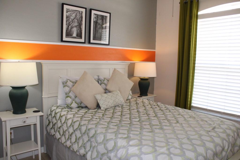 This spacious bedroom features a comfortable queen-size bed flanked by matching bedside lamps