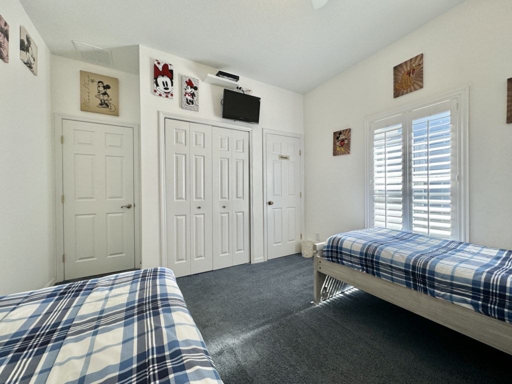 Twin bedroom with storage, closet space, and TV for a comfortable stay.