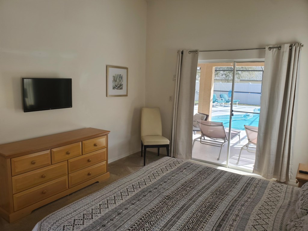 Master bedroom with king bed, ceiling fan. Pool access