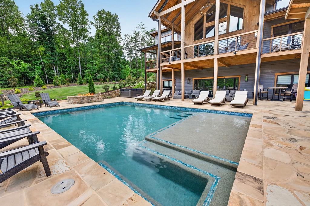 Expansive outdoor pool area with loungers and lush forest views, perfect for relaxation.