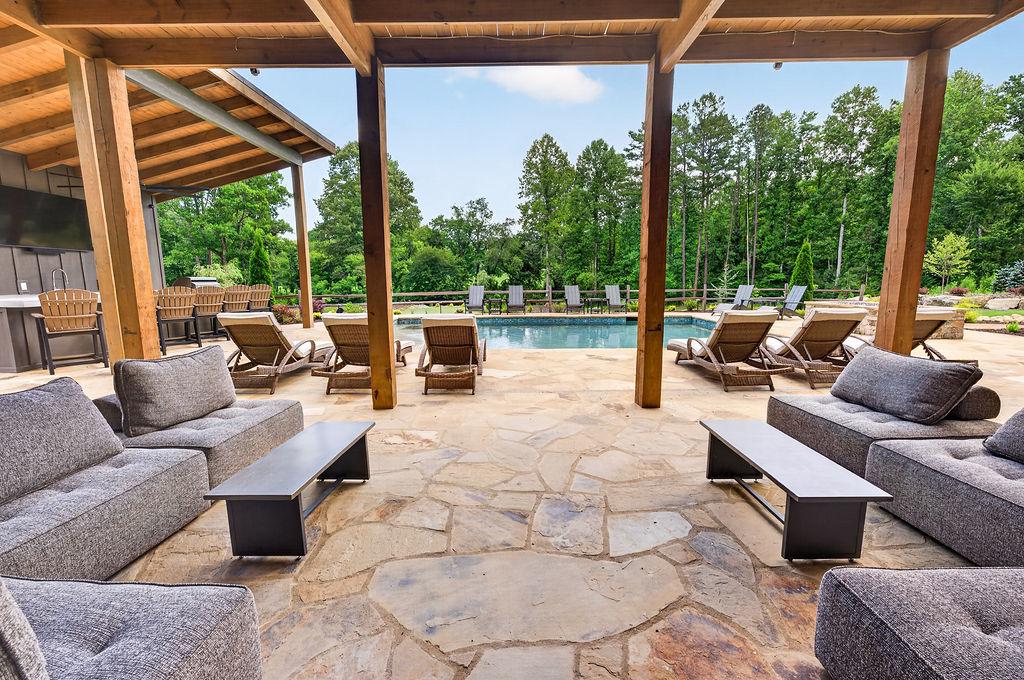 Relaxing patio with cozy seating and views of the pool and lush greenery.