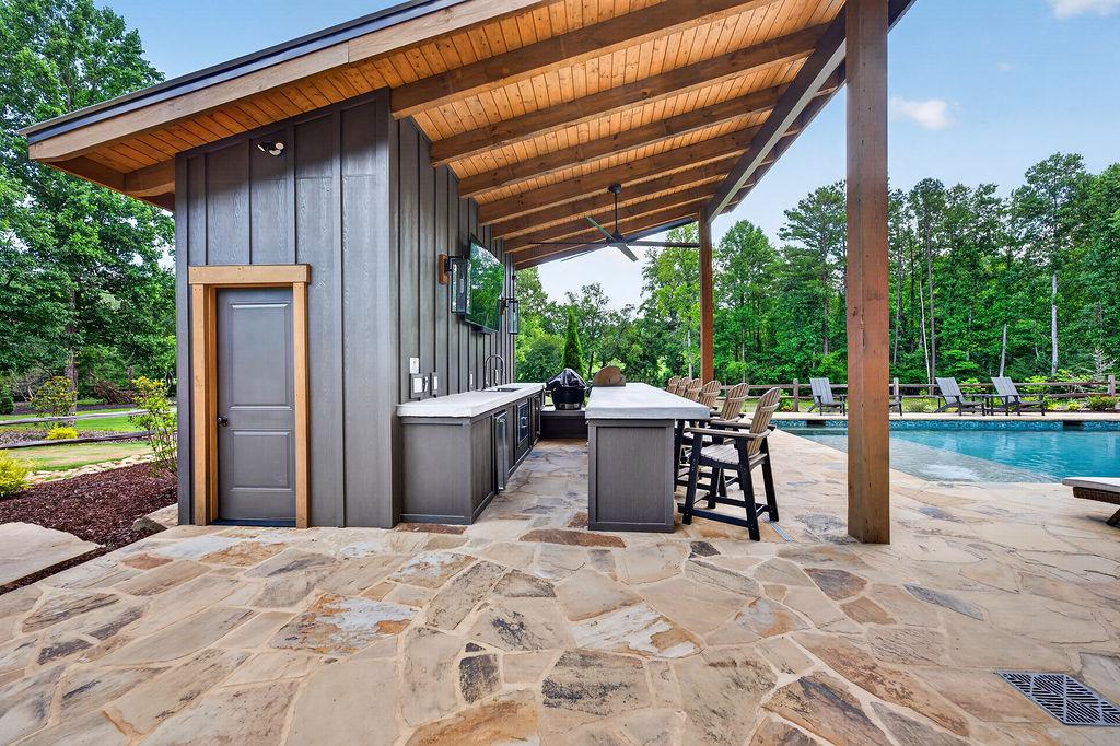 Outdoor kitchen and bar area with poolside seating, perfect for entertaining and relaxation.