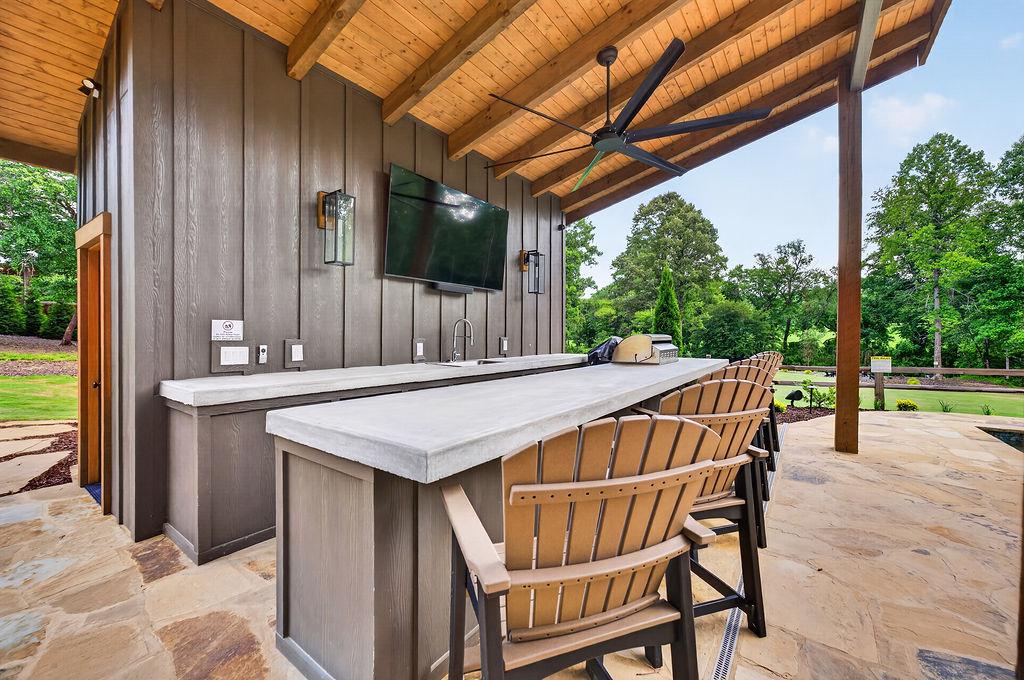 Outdoor bar area with seating, TV, and scenic garden views for relaxing evenings.
