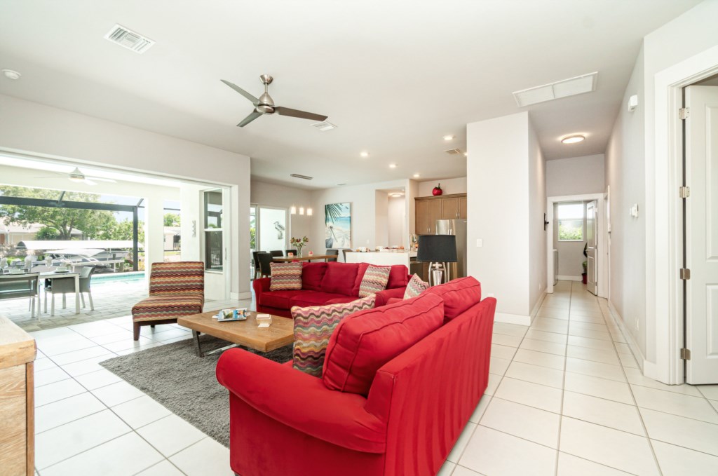 Spacious and inviting living area with vibrant red sofa, opening up to a sunny poolside view.
