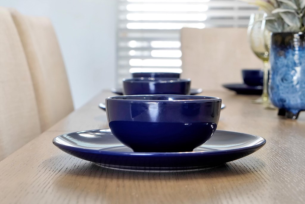 Sleek navy blue dishes sit atop a wooden dining table, inviting space for meals and gatherings and dining experience!