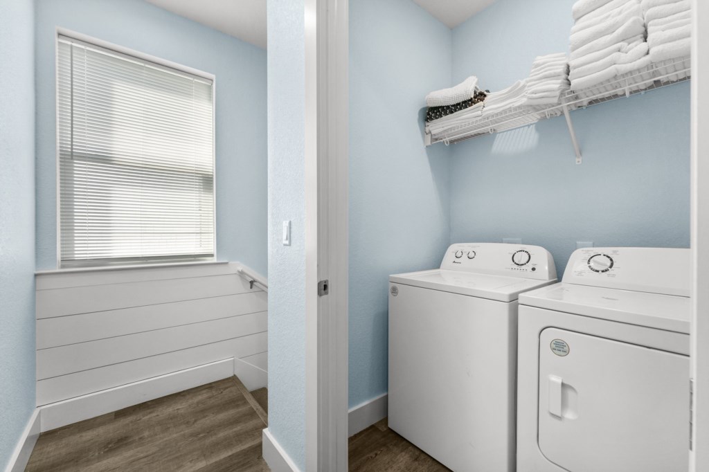 Convenient laundry room with modern appliances and storage shelf.