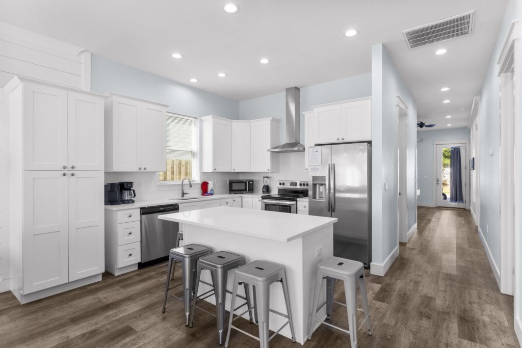Modern kitchen with bar seating and stainless steel appliances.