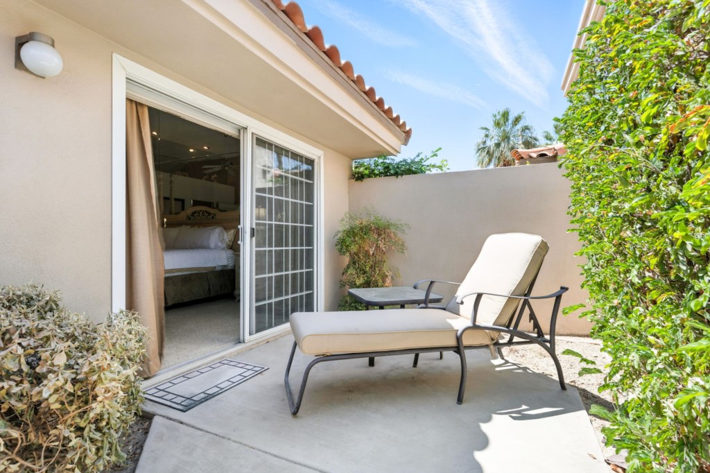 Private patio with lounging chairs, rejuvenating space leading to cozy bedroom.