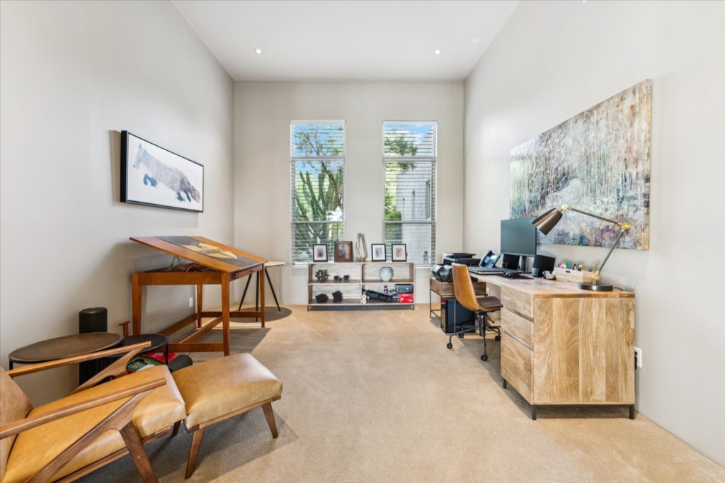 Modern home office with a large desk, comfortable seating, and ample natural light.